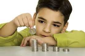 پسر بچه ای که لباس خردلی رنگ پوشیده و بر روی میز در حال چیدن سکه ها می باشد