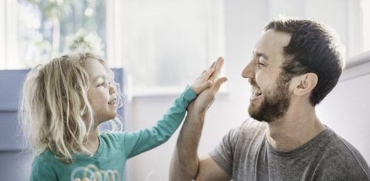 دختر و پدری در کنار یک میز دست بر هم می کوبند و در حقیقت پدر او را تشویق می کند