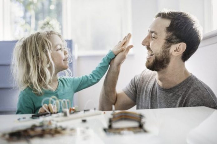 دختر و پدری در کنار یک میز دست بر هم می کوبند و در حقیقت پدر او را تشویق می کند