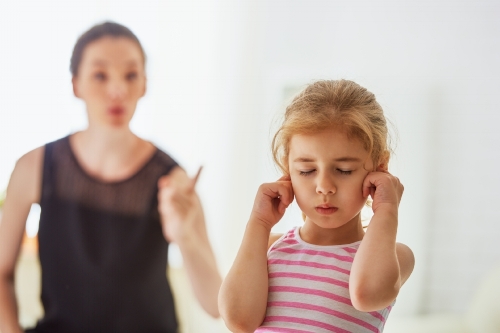 دختری که دست در گوشش کرده که حرفهای مادرش را نشنود
